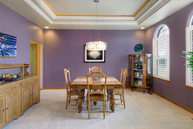 dining area with crown molding, a tray ceiling, an inviting chandelier, and light carpet