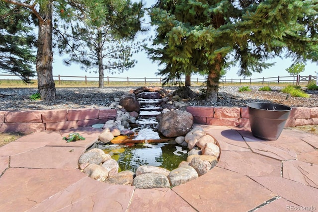 view of patio with a garden pond and fence