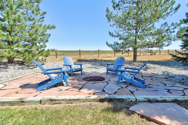 view of patio / terrace featuring an outdoor fire pit, a rural view, and fence