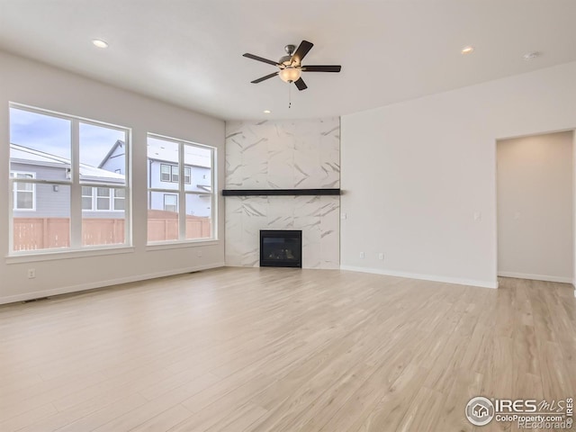 unfurnished living room featuring ceiling fan, light hardwood / wood-style floors, and a fireplace