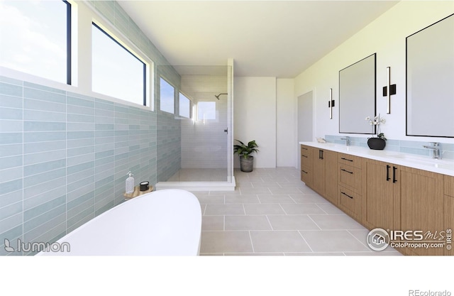 bathroom with dual vanity, tiled shower, tile patterned flooring, and tile walls