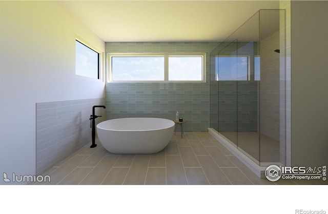 bathroom with independent shower and bath, tile patterned flooring, and tile walls