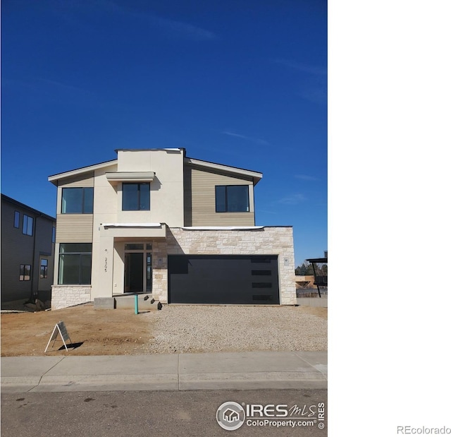 contemporary house featuring an attached garage, stone siding, driveway, and stucco siding