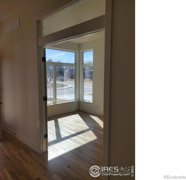 spare room with baseboards, visible vents, and dark wood-type flooring