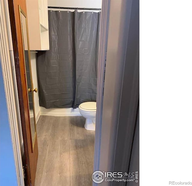 bathroom featuring hardwood / wood-style flooring, a shower with curtain, and toilet