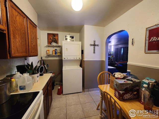 kitchen featuring stacked washer / dryer, light tile patterned flooring, and white range with electric cooktop