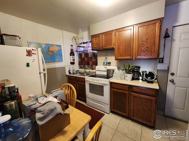 kitchen featuring sink, white appliances, and light tile patterned floors