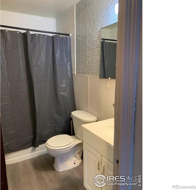 full bathroom with toilet, shower / bath combo with shower curtain, wood-type flooring, and vanity