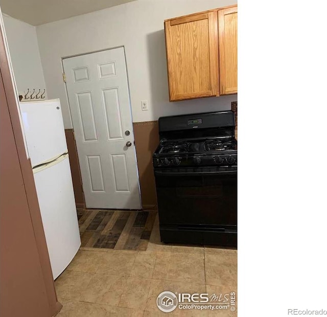 kitchen with white fridge, gas stove, and light brown cabinets