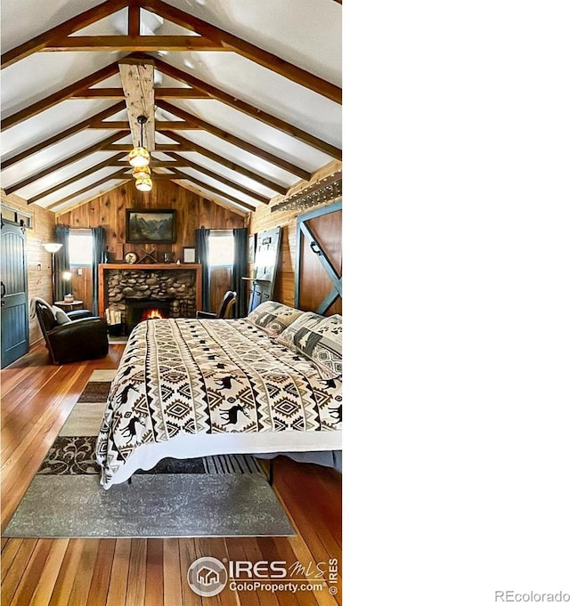 bedroom with vaulted ceiling with beams, hardwood / wood-style floors, a stone fireplace, and wooden walls