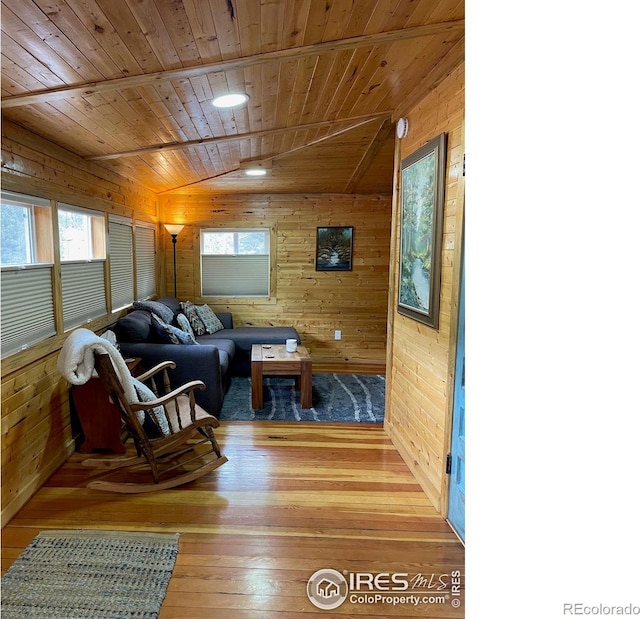 living room with plenty of natural light, hardwood / wood-style flooring, wood walls, and wood ceiling