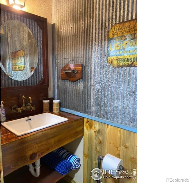 bathroom featuring wood walls and sink