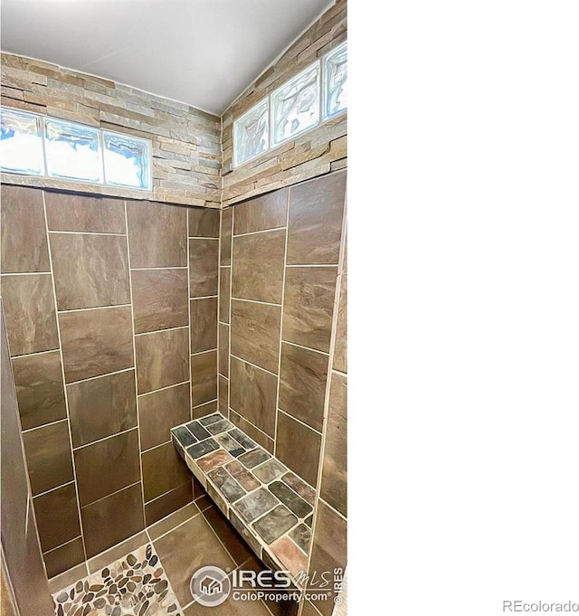 bathroom featuring tile floors, plenty of natural light, and a tile shower