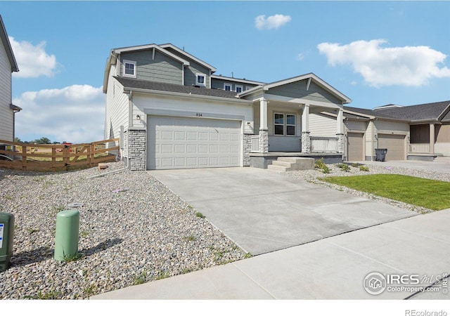 craftsman-style home featuring fence, driveway, a porch, an attached garage, and stone siding