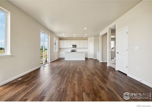 unfurnished living room with recessed lighting, visible vents, baseboards, and dark wood-type flooring