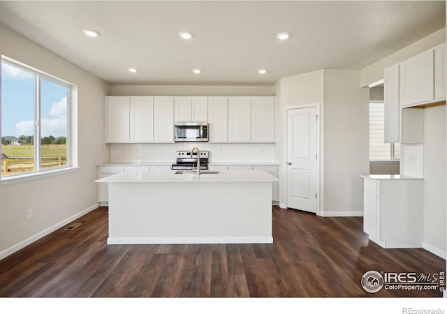 kitchen with a kitchen island with sink, appliances with stainless steel finishes, light countertops, and a sink