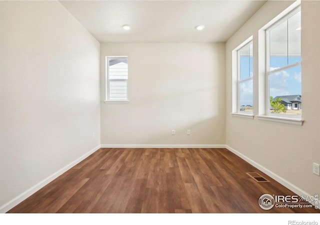 empty room featuring visible vents, baseboards, and wood finished floors