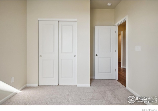 unfurnished bedroom featuring carpet flooring, baseboards, and a closet