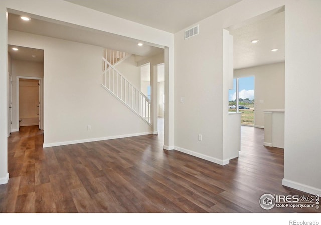 empty room with visible vents, stairway, baseboards, and wood finished floors