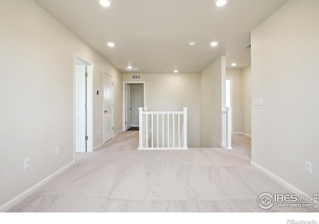 spare room with recessed lighting, light colored carpet, and baseboards