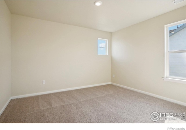 carpeted spare room featuring visible vents and baseboards