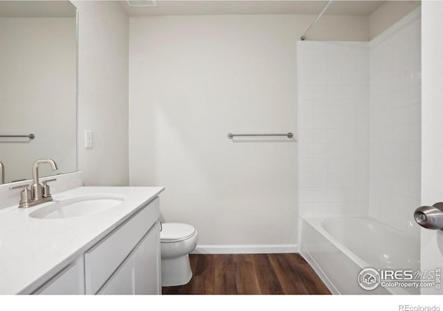 bathroom with toilet, wood finished floors, baseboards, bathing tub / shower combination, and vanity