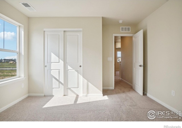 unfurnished bedroom featuring multiple windows, visible vents, and carpet floors