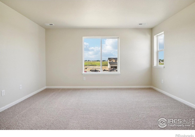 carpeted spare room with visible vents and baseboards