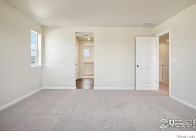 unfurnished bedroom with visible vents, multiple windows, carpet, and baseboards