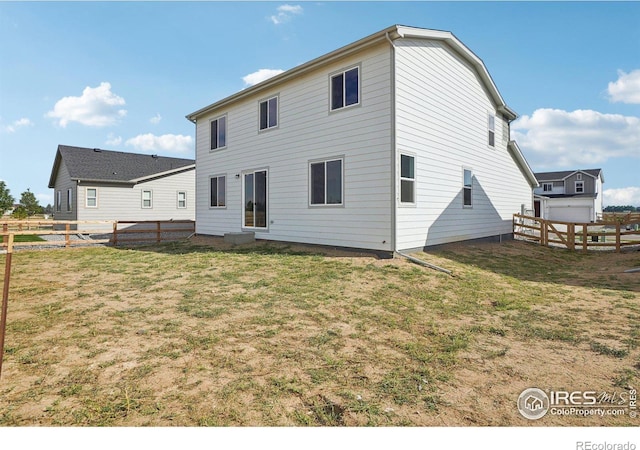 rear view of house featuring a lawn and a fenced backyard