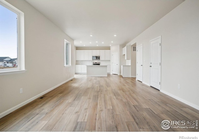 unfurnished living room with light wood-style floors, visible vents, baseboards, and recessed lighting