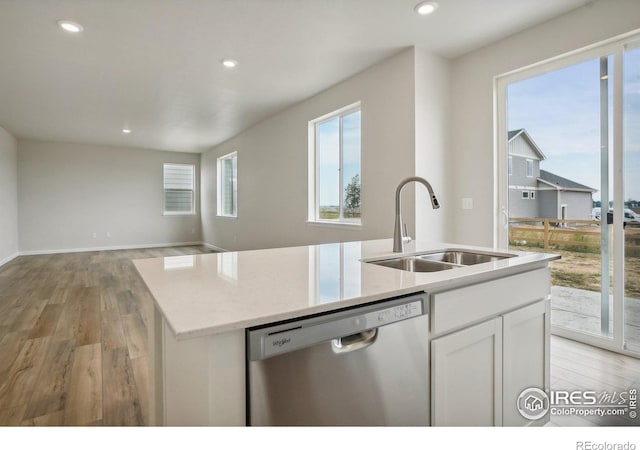 kitchen featuring light stone counters, stainless steel dishwasher, a kitchen island with sink, white cabinetry, and a sink