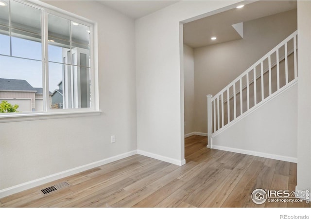 empty room featuring recessed lighting, visible vents, stairway, light wood-style floors, and baseboards