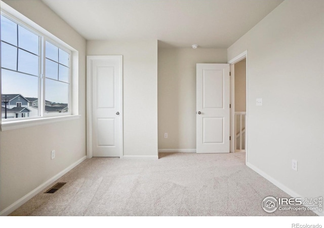 unfurnished bedroom with light carpet, baseboards, and visible vents