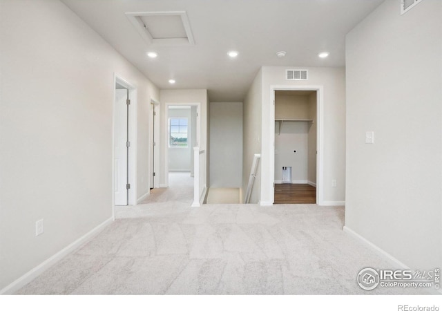 unfurnished bedroom featuring recessed lighting, visible vents, a spacious closet, attic access, and light carpet