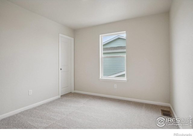 empty room featuring carpet floors, visible vents, and baseboards