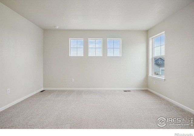 spare room with light carpet, visible vents, and baseboards