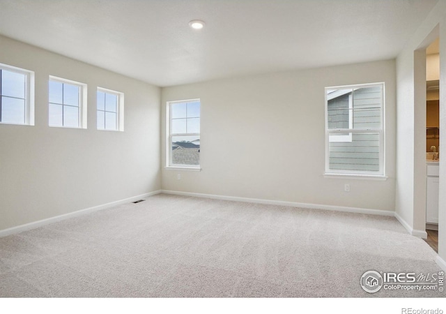 unfurnished room featuring light carpet, visible vents, and baseboards