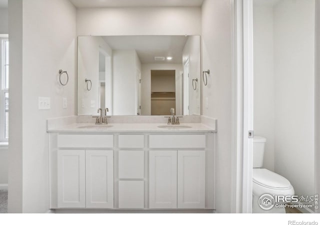 full bath with double vanity, a sink, and toilet