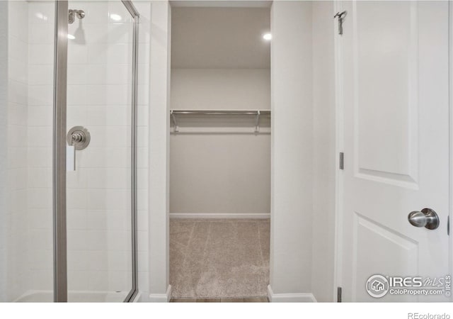 full bath with a walk in closet and a shower stall