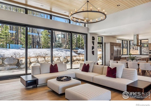 living room featuring an inviting chandelier, light hardwood / wood-style flooring, and wooden ceiling