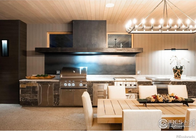 kitchen with pendant lighting, wall chimney range hood, wooden ceiling, and wood walls