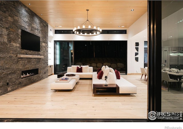 living room featuring wood-type flooring, a fireplace, a chandelier, and wooden ceiling