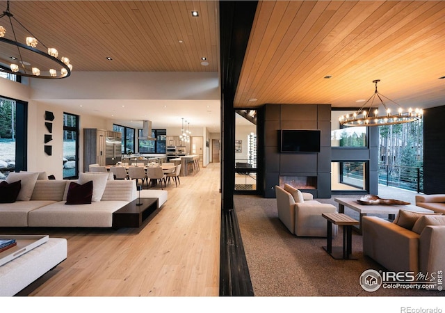 living room with light hardwood / wood-style floors, a notable chandelier, wood ceiling, and a fireplace