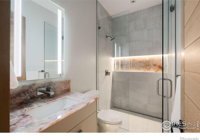 bathroom with vanity, toilet, and a shower with shower door