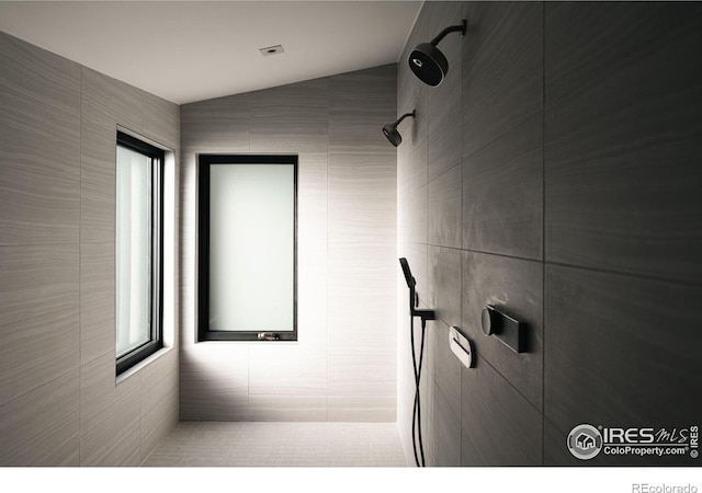 bathroom with tiled shower and vaulted ceiling