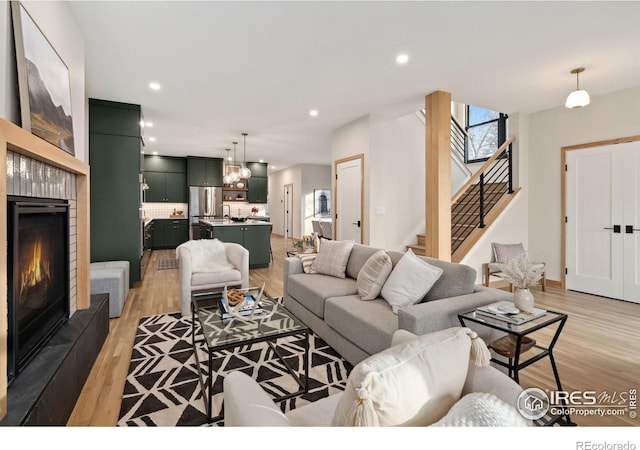 living room featuring a tile fireplace, light hardwood / wood-style flooring, and a chandelier