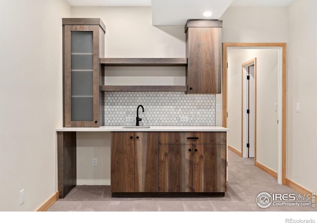 kitchen with sink, backsplash, and light carpet