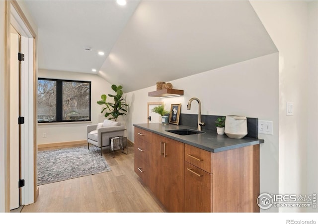 kitchen featuring vaulted ceiling, light wood-type flooring, and sink