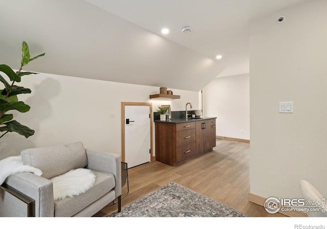 living area featuring vaulted ceiling, light hardwood / wood-style floors, and sink